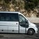 A late model minibus parked near a hillside